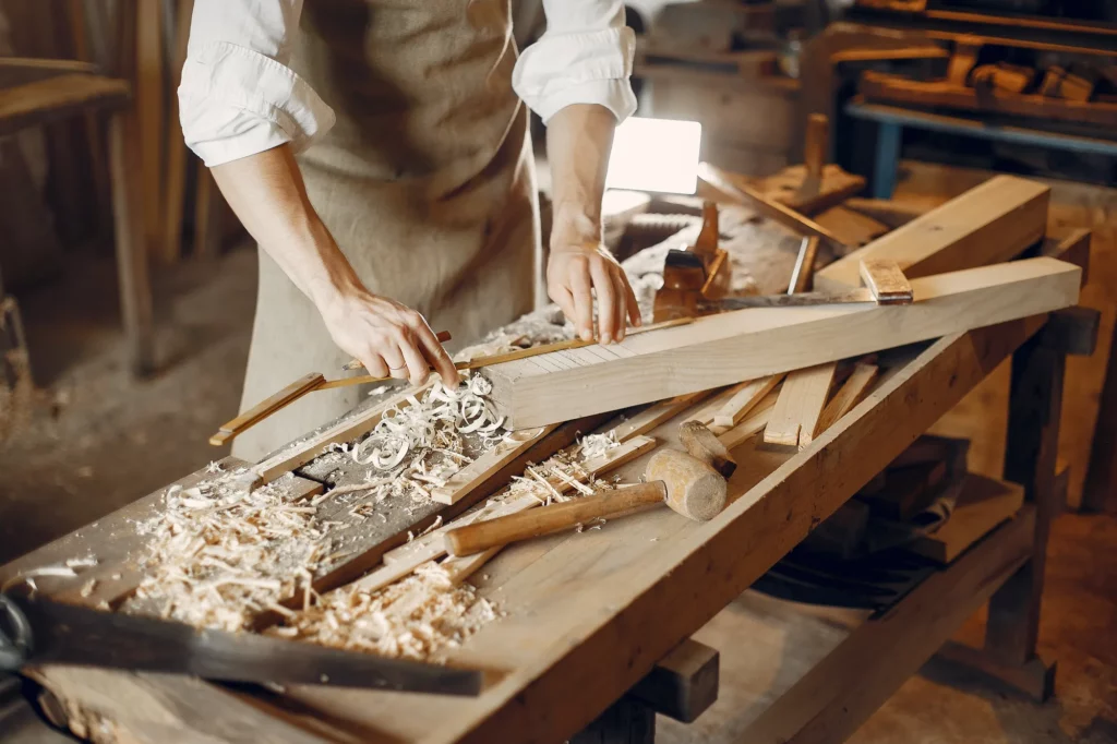 Menuisier rabotant une pièce de bois massif à l'atelier